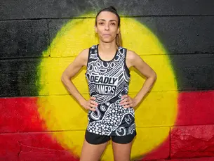 Georgia Weir, founder of the First Nations-led run club - Deadly Runners - standing in front of an Aboriginal Flag artwork