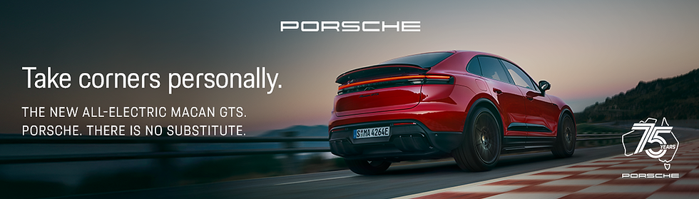 Red electric Porsche Macan GTS on a road at dusk.