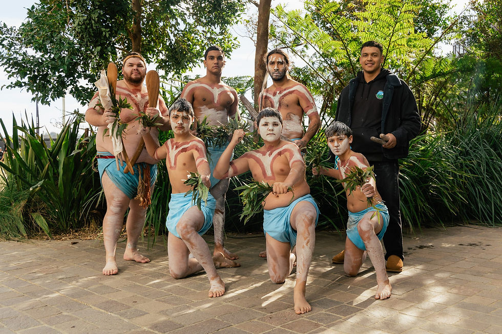 Indigenous dancers in traditional body paint outdoors.