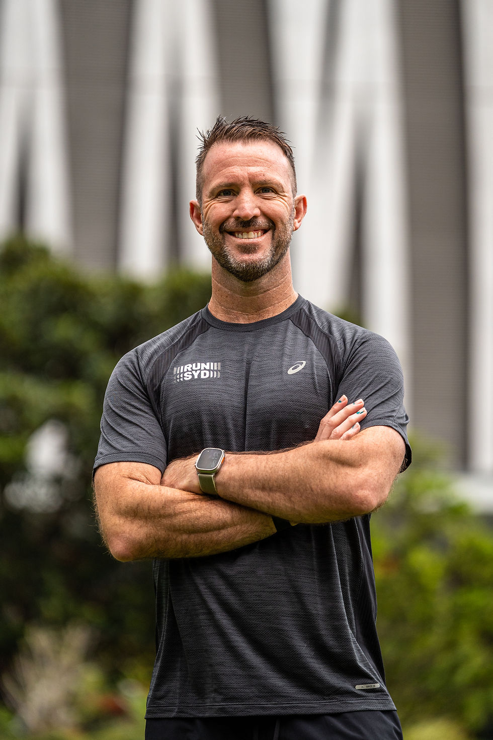 Smiling TCS Sydney Marathon Run Club coach with arms crossed.