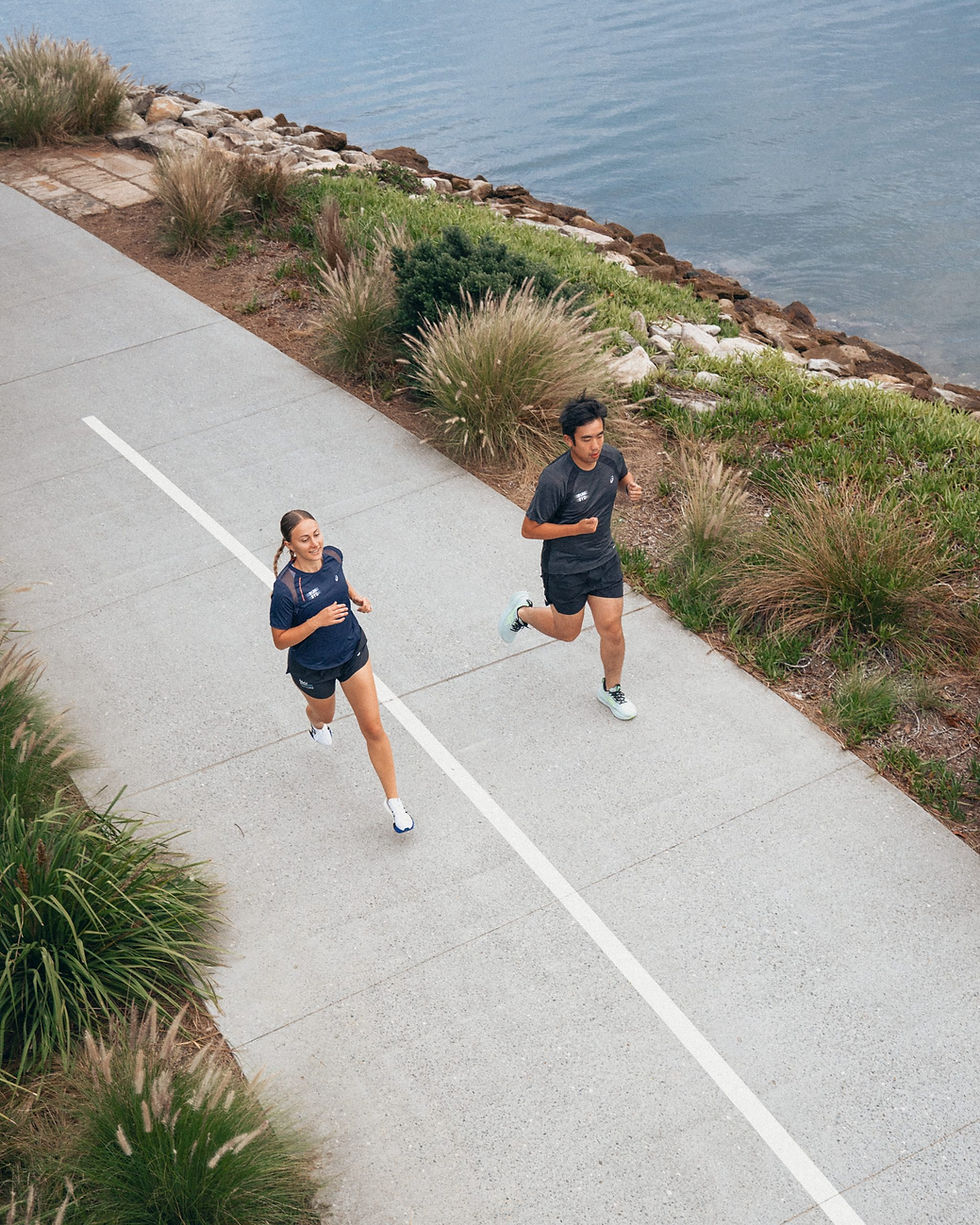 Two people jogging on a coastal path by the water.