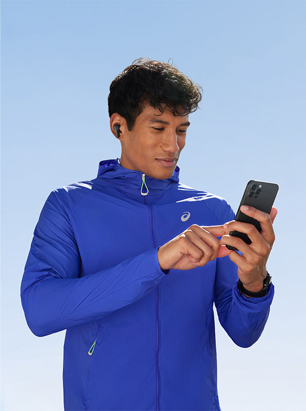Runner in ASICS jacket using a smartphone