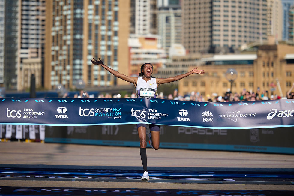 Runner crossing TCS Sydney Marathon finish line with arms raised