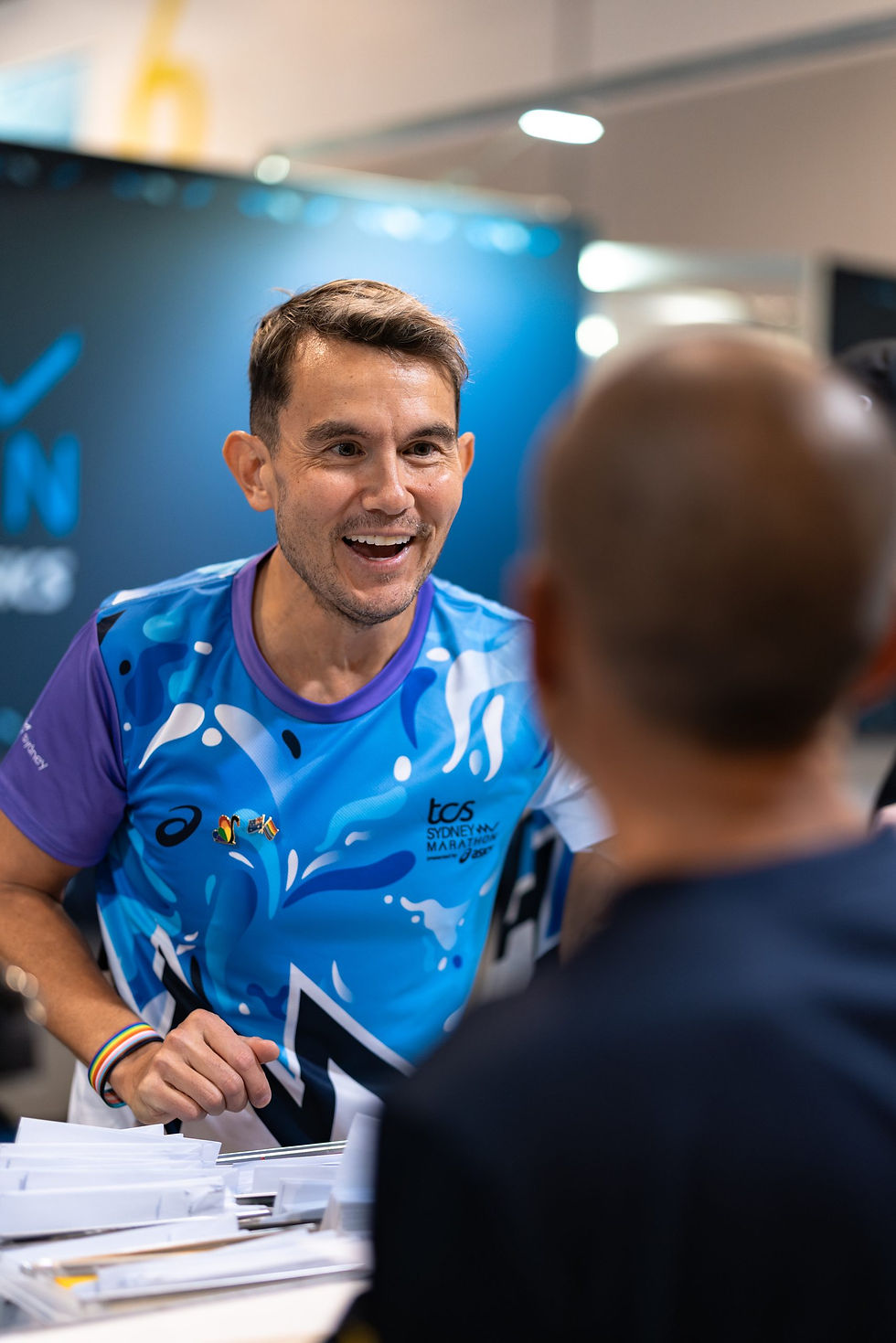 Smiling man in blue athletic shirt talking to a visitor